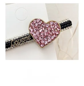 Detail view of pink rhinestone heart hairpin with Loveme metal lettering and braided strap