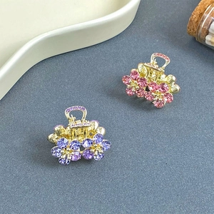Close-up of mini floral hair clips with sparkling crystals in pink and purple colors