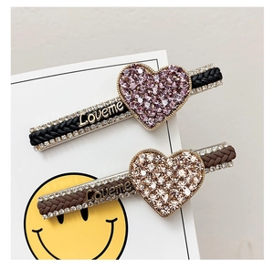 Detail view of woven rhinestone hair clips with heart design and Loveme engraving