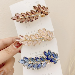 Three crystal leaf hair clips in gold finish displayed on a white jewelry card