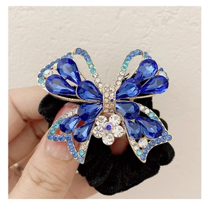 Dettaglio di elastico in velluto con farfalla di cristallo blu e strass lucidi