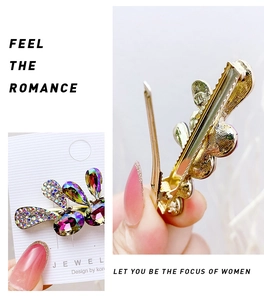 Detailed close-up of a golden butterfly hair clip with colorful rhinestones and leaf pattern