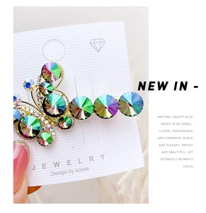 Close-up of golden butterfly hair clip with iridescent rainbow crystals on display card