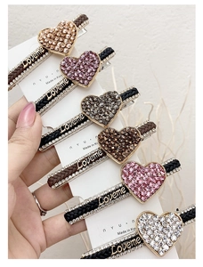 Close-up of sparkling rhinestone heart hair clips with woven straps and Loveme letters