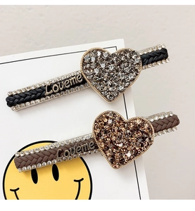Detail view of woven leather hair clips with rhinestone hearts and Loveme metal letters
