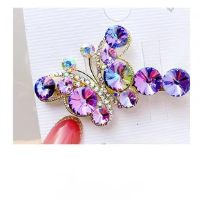 Detail of a gold alloy butterfly hair clip with large purple crystals on a card
