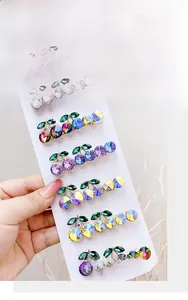 Detailed macro view of cherry-shaped hair clips with green leaves and aurora rhinestones