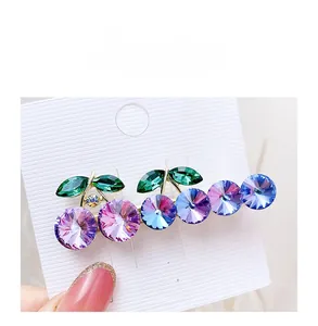 Macro detail of cherry-shaped clip with purple crystal rhinestones and green leaves