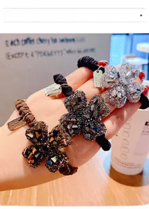 Dettaglio di elastici per capelli a quadrifoglio con strass in marrone, grigio e bianco
