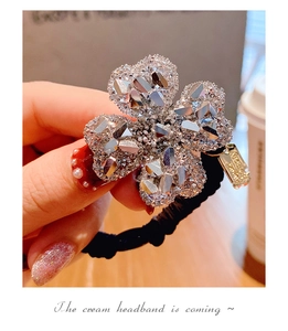 Dettaglio dell'elastico per capelli a quadrifoglio con strass e ciondolo handmade