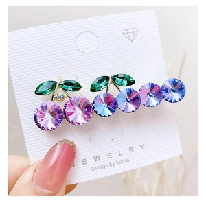 Macro shot of a cherry-shaped hair clip with purple crystal rhinestones on a gold base