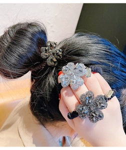 Dettaglio di elastici per capelli con quadrifoglio di strass nei colori argento e grigio