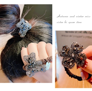 Dettaglio macro di ciondoli a quadrifoglio e orsetto con strass su elastici per capelli