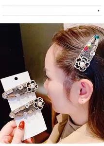 Détail de l'ensemble de barrettes camélia avec strass brillants et perles blanches
