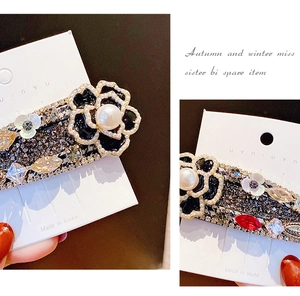 Détail de la pince à cheveux camélia avec strass et incrustation de perles blanches