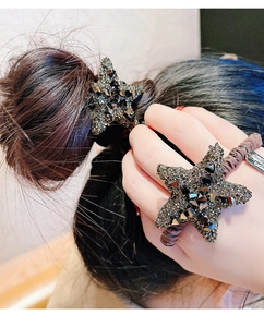 Primo piano di un elastico per capelli a stella con cristalli grigi su polso e capelli