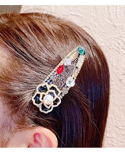 Détail de la pince à cheveux camélia vintage avec strass colorés et perle blanche