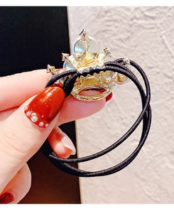 Dettaglio di un elastico corona dorata con strass e corde elastiche nere a tre fili
