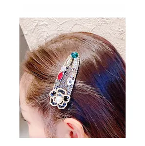 Barrette camélia baroque avec strass colorés et perle portée sur les cheveux