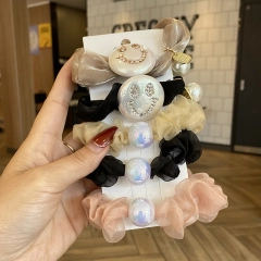 Detail view of 5-piece scrunchie set featuring smiley buttons and iridescent pearls