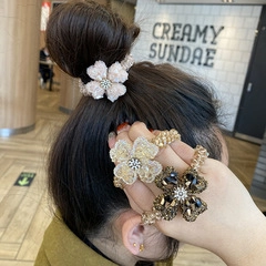 Detailed view of three beaded floral hair ties in pink, champagne, and brown on a model