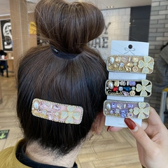 Detail showing four multi-color rhinestone hair barrettes with pearls and clover motifs