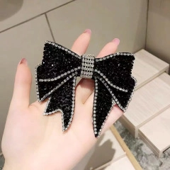 Detail shot of a black satin bow hair accessory adorned with sparkling white rhinestones