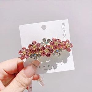 Dettaglio della molletta con fiore in cristallo rosa con base dorata e strass luminosi