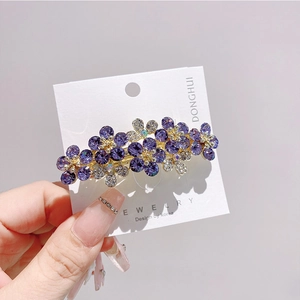 Vista dettagliata della molletta per capelli con fiori di strass viola e oro