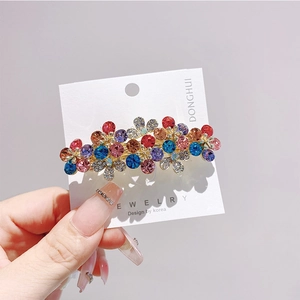 Dettaglio del fermaglio per capelli floreale con strass colorati su base in lega dorata