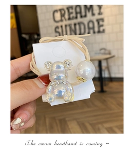 Detailed macro of iridescent resin bear charm with rhinestones and pearl on hair elastic