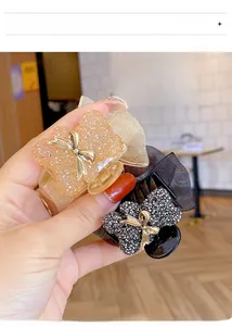 Close-up of sparkling rhinestone hair claws with organza bows in black and champagne gold