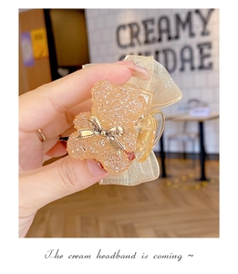 Detailed view of a cute bear hair claw clip with rhinestones and organza bow detail
