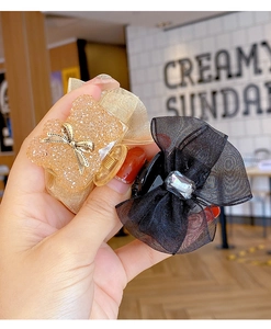 Detail showing champagne glitter and black organza bow hair claws with rhinestones