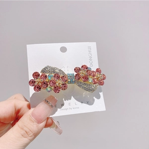 Detail of Korean bow hair clip featuring sparkling pink and white rhinestones on gold base