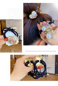 Detailed view of heart-shaped hair tie with oversized pearl and colorful crystals