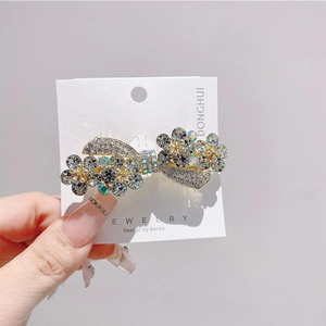 Detail of flower bow hair clip with blue rhinestones and gold metal base design