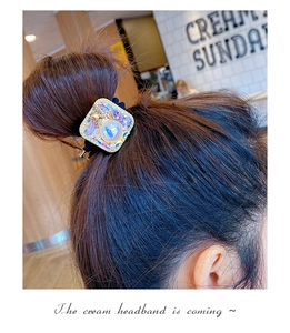 Detailed view of square hair tie with colorful rhinestones and pearl on model
