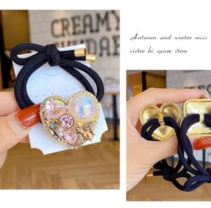 Detail of heart-shaped hair tie with pink crystals, blue pearls and golden bee accent