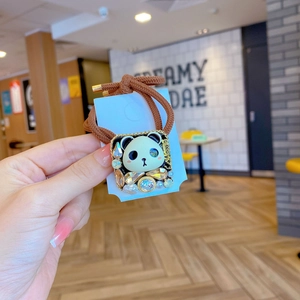 Détail d'un chouchou panda avec des strass et un élastique tressé marron