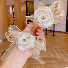 Close-up of a cream rose hair claw set with sparkling rhinestones and organza bow