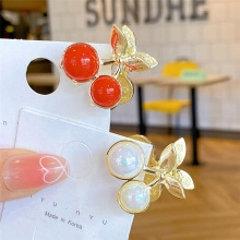 Detailed close-up of cherry hair clip with red and pearl fruits on a brand card