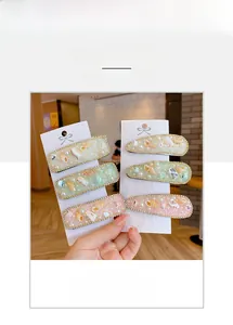 Dettaglio di fermagli per capelli con fiori di conchiglia, perle e bordi di strass colorati