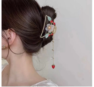Detailed view of golden hair claw clip with pearls, flowers, and strawberry tassel fringe