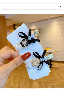 Detailed view of handmade camellia pearl bow hair clips set against a display card