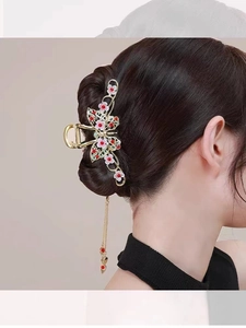 Detail of golden butterfly hair claw with pink flowers and elegant metal tassels