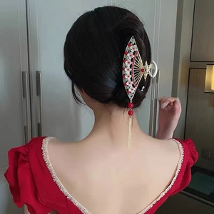 Chinese style gold fan-shaped hair claw with pearls and tassels on long dark hair