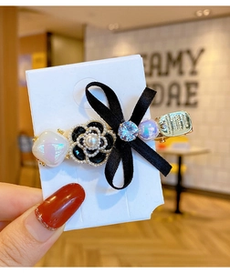 Detailed close-up of a black silk bow hair clip with camellia flower and pearls