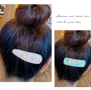 Dettaglio di fermagli per capelli con perle e fiori di conchiglia rosa e verdi