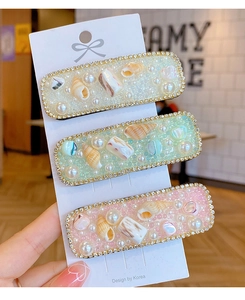 Dettaglio di tre fermagli per capelli boho con fiori di conchiglia, perle e strass lucidi